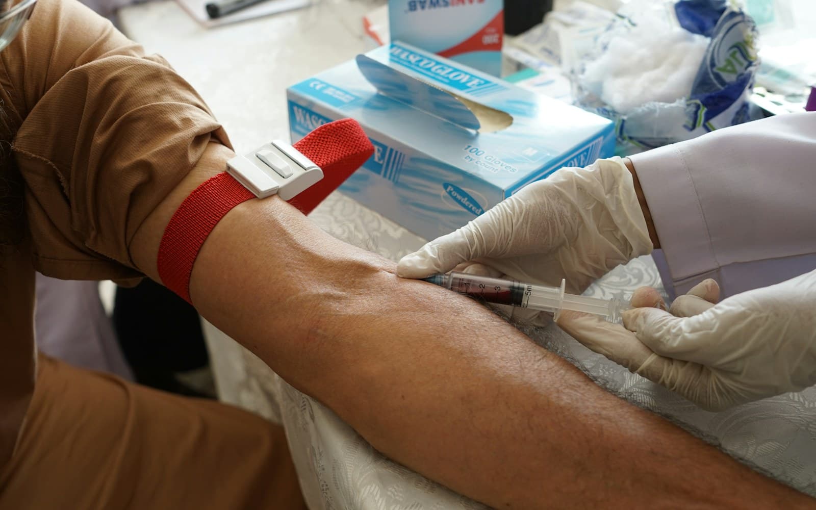 A healthcare professional preparing to take a blood sample from a patient’s arm